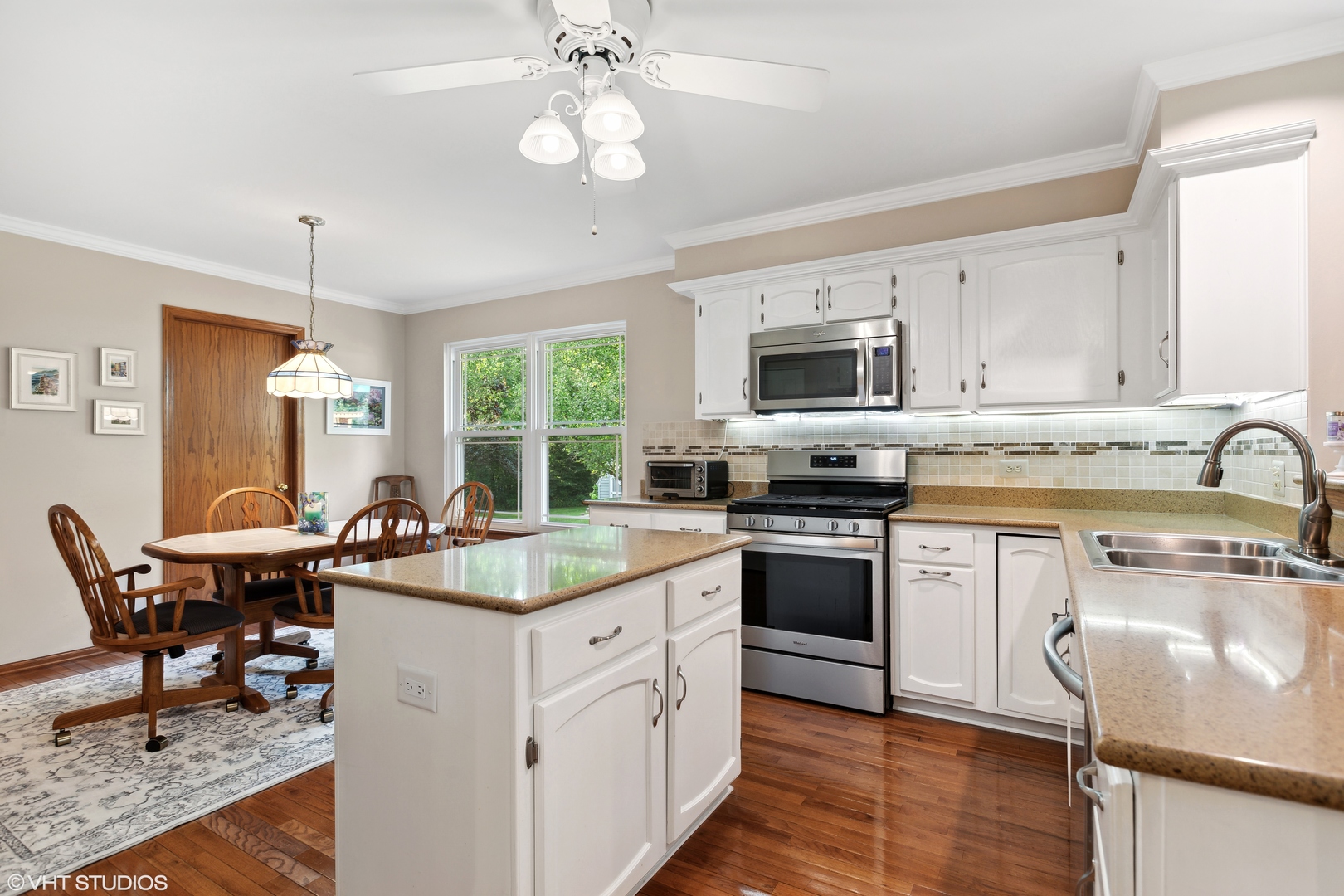 966 Ridgewood Drive Cary, IL 60013 - Photo 7 of 31 a kitchen with stainless steel appliances granite countertop a stove top oven a sink dishwasher a dining table and chairs with wooden floor