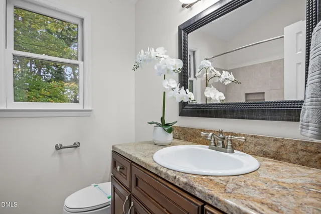 a bathroom with a granite countertop sink a toilet and a mirror