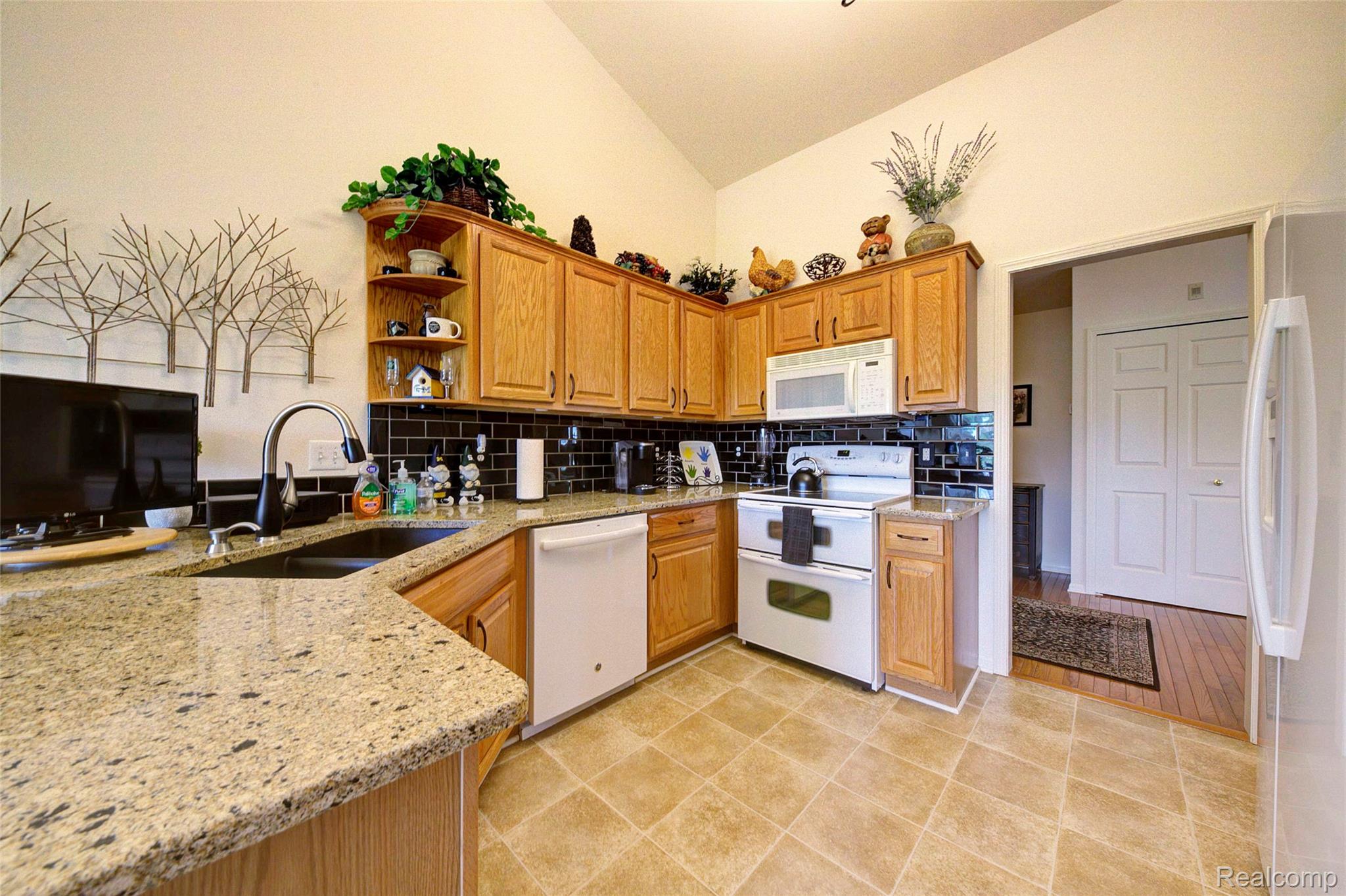 2577 Cleveland Way Canton, MI 48188 - Photo 14 of 34 Kitchen featuring light stone counters, vaulted ceiling, white appliances, decorative backsplash, and open shelves