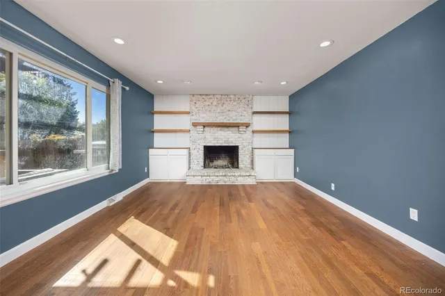 a view of empty room with fireplace and wooden floor