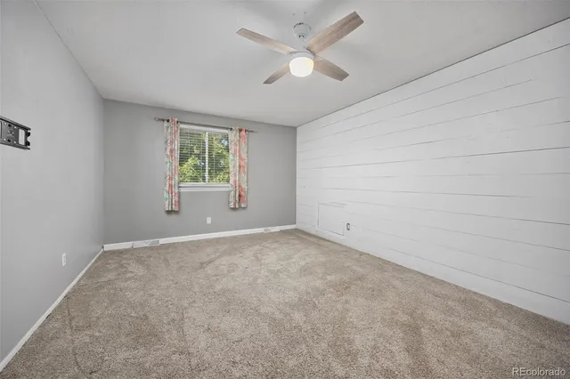 an empty room with a window and a ceiling fan