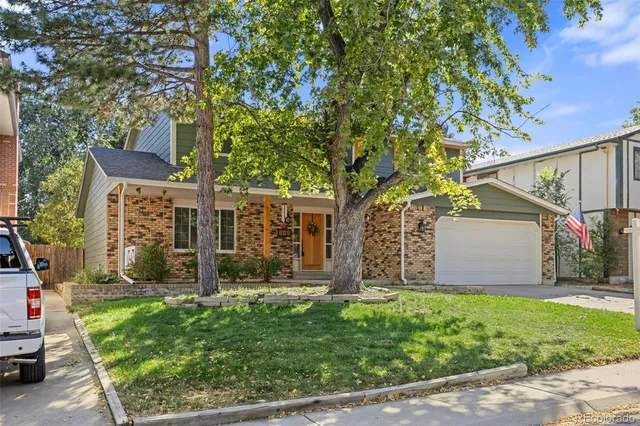 a view of a house with a small yard and a large tree