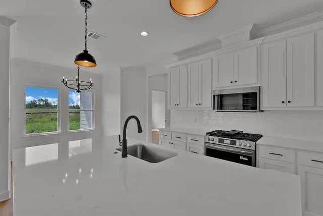 a view of an empty room with window and chandelier fan