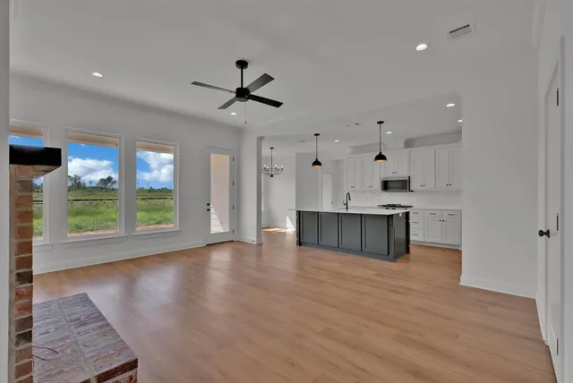 a large kitchen with stainless steel appliances granite countertop a stove a sink and white cabinets with wooden floor