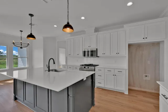 a kitchen with stainless steel appliances a sink a stove a refrigerator and center island