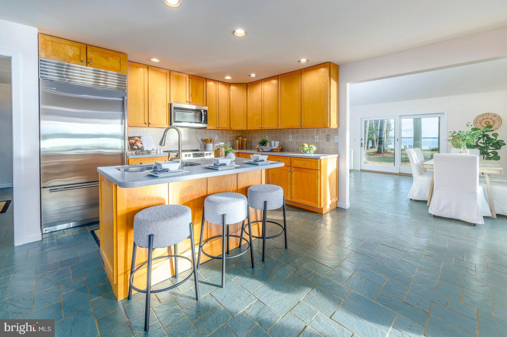 7930 Church Neck Road St. Michaels, MD 21663 - Photo 24 of 41 a kitchen with stainless steel appliances granite countertop wooden floor dining table and chairs