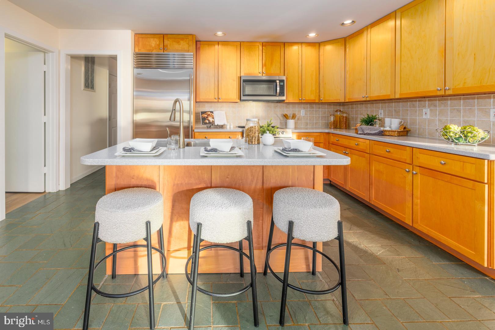 7930 Church Neck Road St. Michaels, MD 21663 - Photo 25 of 41 a kitchen with stainless steel appliances a dining table chairs and a refrigerator