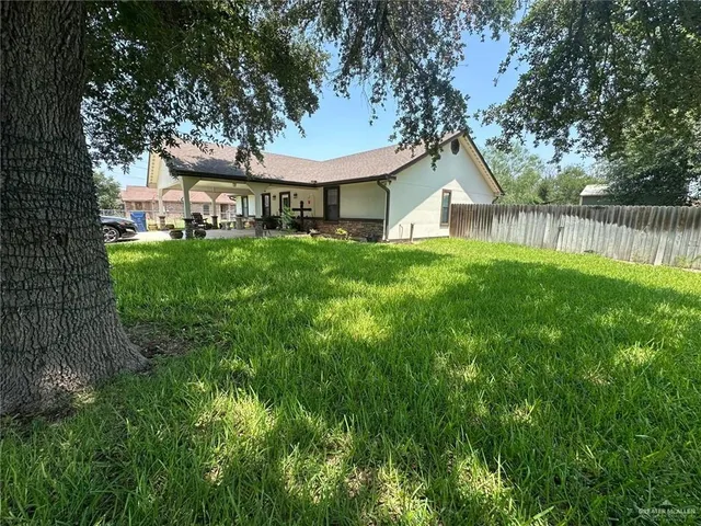 a view of a house with a big yard plants and large trees