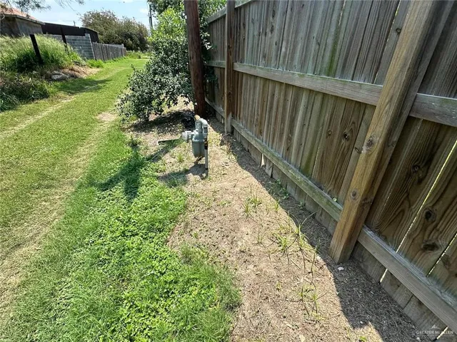 a view of small garden in the backyard with large trees and wooden fence
