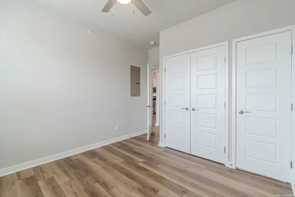 a view of empty room with wooden floor and fan