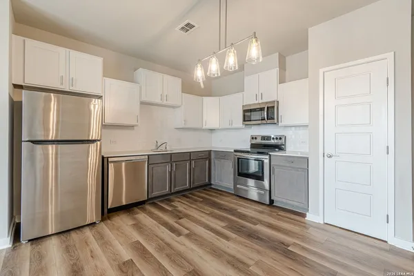 a kitchen with granite countertop a refrigerator stove top oven and sink