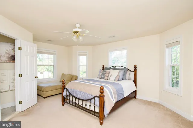 a spacious bedroom with a bed a ceiling fan and a dresser