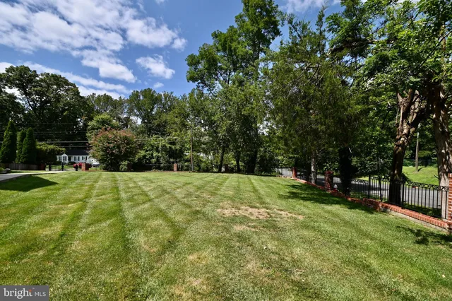 a view of a big house with a big yard and large trees