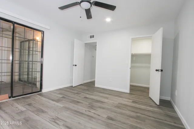 an empty room with wooden floor and windows