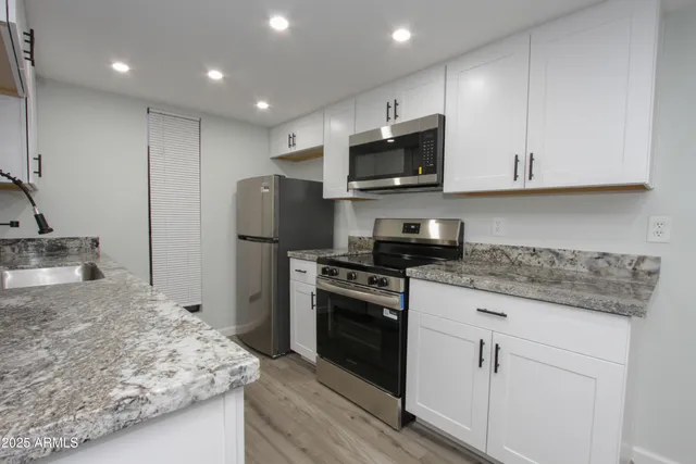 a kitchen with kitchen island granite countertop a sink stainless steel appliances and white cabinets