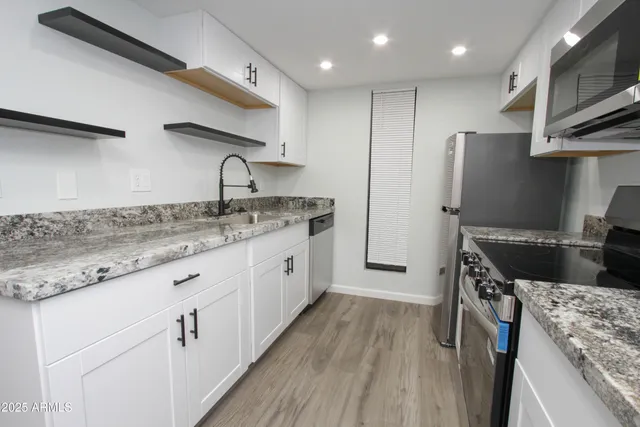 a kitchen with granite countertop a sink a counter space stainless steel appliances and cabinets