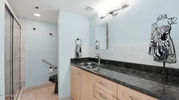 a bathroom with a granite countertop sink a mirror and shower