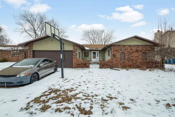 a front view of a house with a yard covered in snow