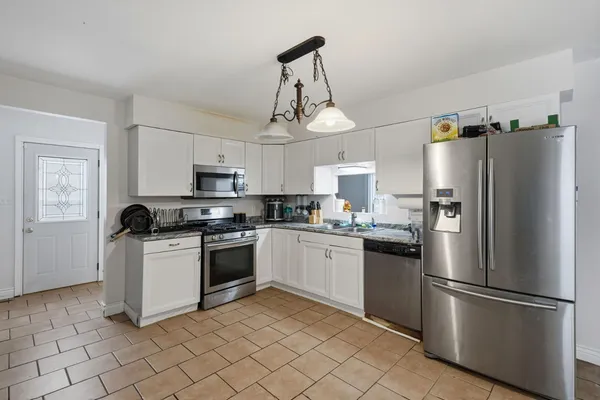 a kitchen with stainless steel appliances granite countertop a refrigerator a stove a sink a microwave and dining table