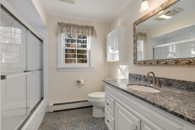 a bathroom with a sink a mirror a toilet and a window