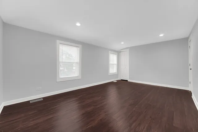 a view of an empty room with wooden floor and window
