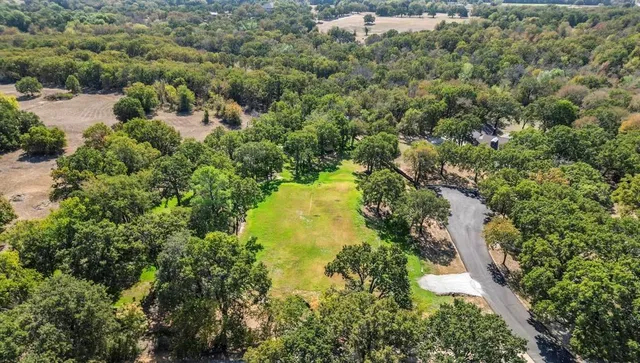an aerial view of residential houses with outdoor space and trees all around
