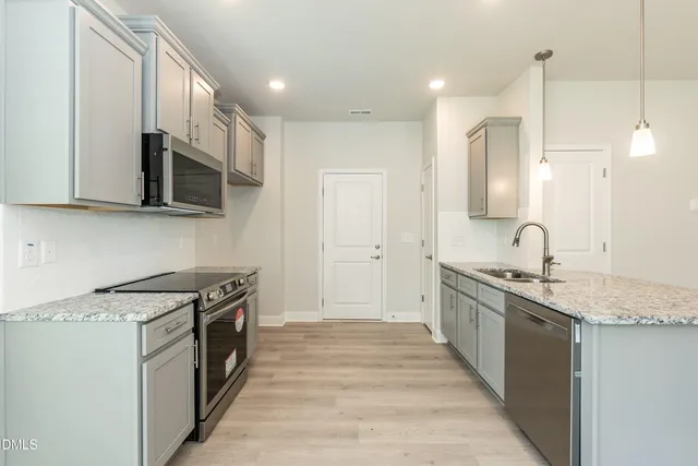 a kitchen with stainless steel appliances granite countertop a stove a sink and a microwave