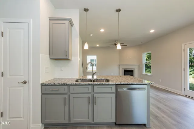 a kitchen with kitchen island granite countertop a sink cabinets and stainless steel appliances