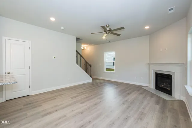 an empty room with wooden floor fireplace and windows