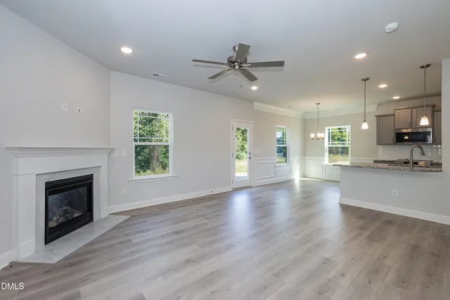 an empty room with wooden floor fireplace and windows