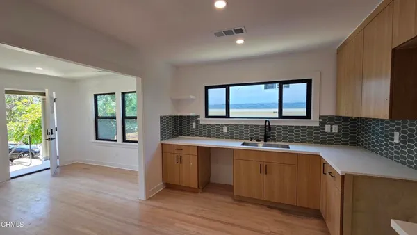 a view of a kitchen with a sink wooden cabinets and a window