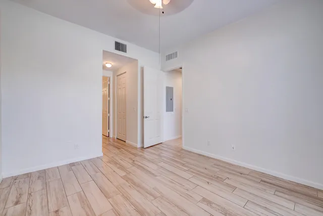 a view of an empty room with wooden floor closet and a chandelier