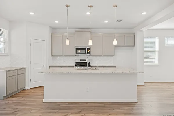 a large white kitchen with kitchen island white cabinets and stainless steel appliances