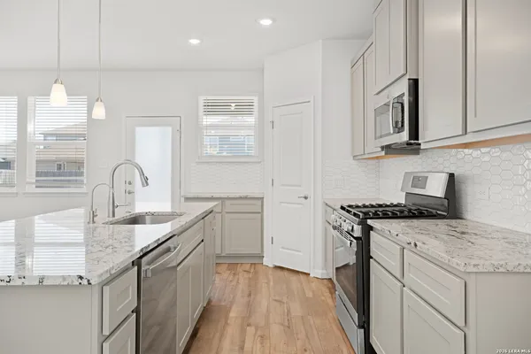 a kitchen with granite countertop a sink stainless steel appliances and cabinets