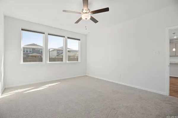an empty room with windows and ceiling fan