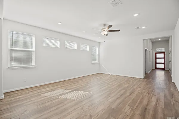 a view of empty room with wooden floor and ceiling fan