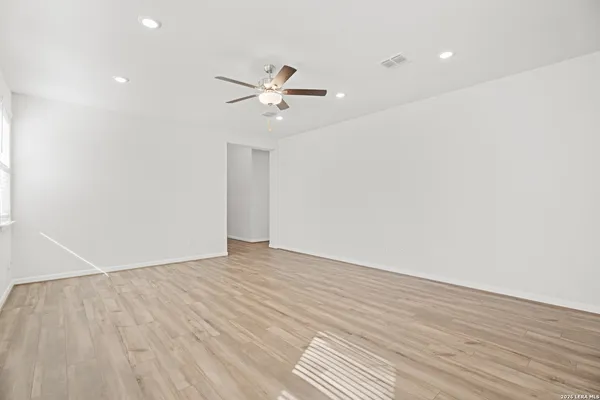 a view of empty room with wooden floor and fan