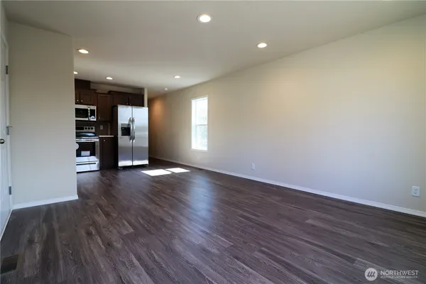 a view of empty room with wooden floor and window