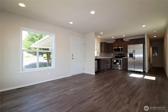 an open kitchen with kitchen island wooden floors appliances and center island