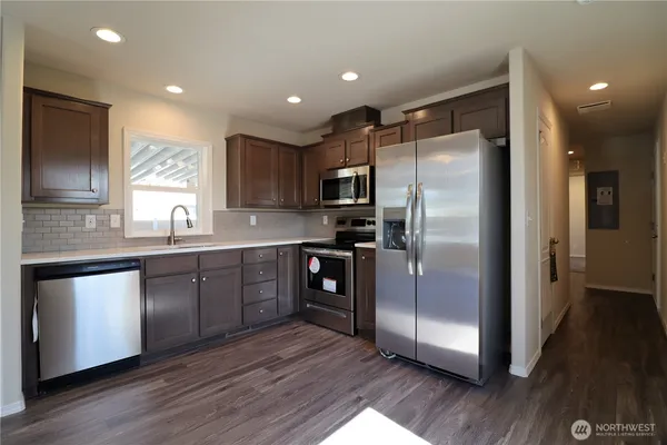 a kitchen with stainless steel appliances granite countertop a refrigerator a sink a stove a microwave and wooden floor