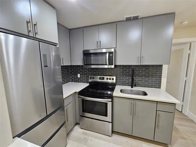 a kitchen with a refrigerator sink and cabinets