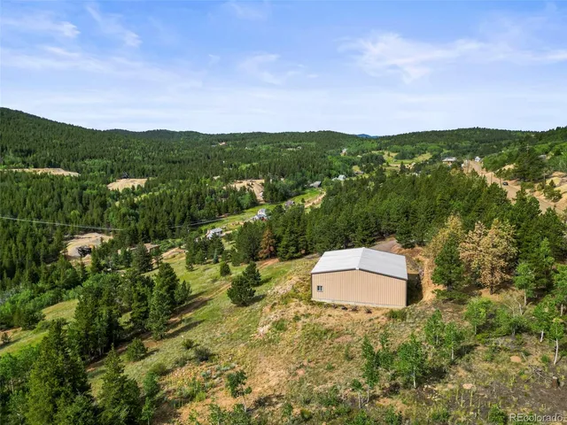 an aerial view of residential house with green space and fog