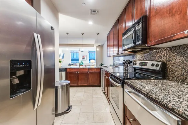 a kitchen with stainless steel appliances granite countertop a refrigerator a stove and a sink