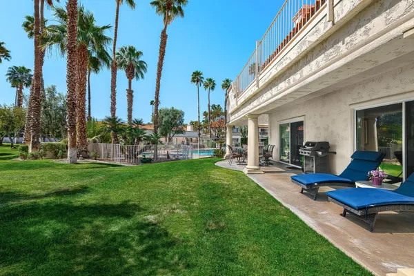 a view of a backyard with table and chairs potted plants and a palm tree