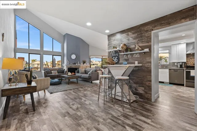a living room with furniture a chandelier a large window and wooden floor