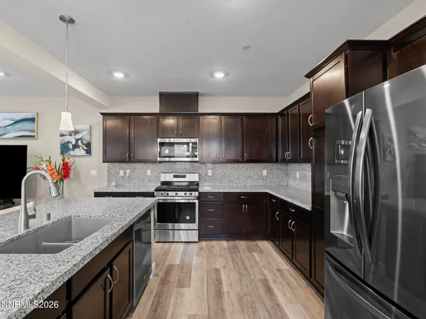 a kitchen with stainless steel appliances granite countertop sink stove top oven and refrigerator
