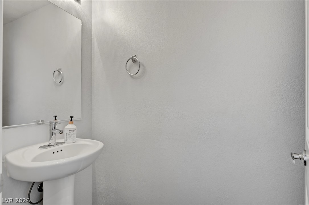 48 Jasmine Point Street Henderson, NV 89074 - Photo 26 of 62 A pristine powder room with a sleek pedestal sink and contemporary fixtures, perfect for guests.