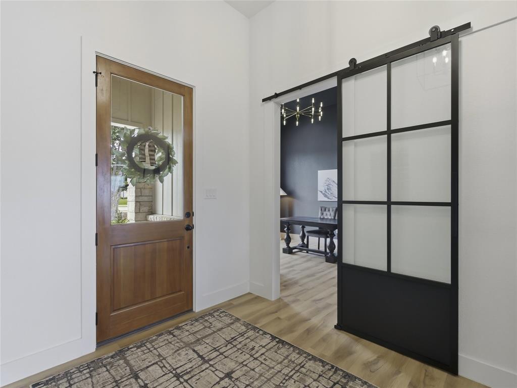 4211 Azalea Way Midlothian, TX 76065 - Photo 6 of 39 Entryway featuring wood-finish flooring, a solid wood entry door with an upper glass panel, and a modern black-framed barn door with frosted glass panels