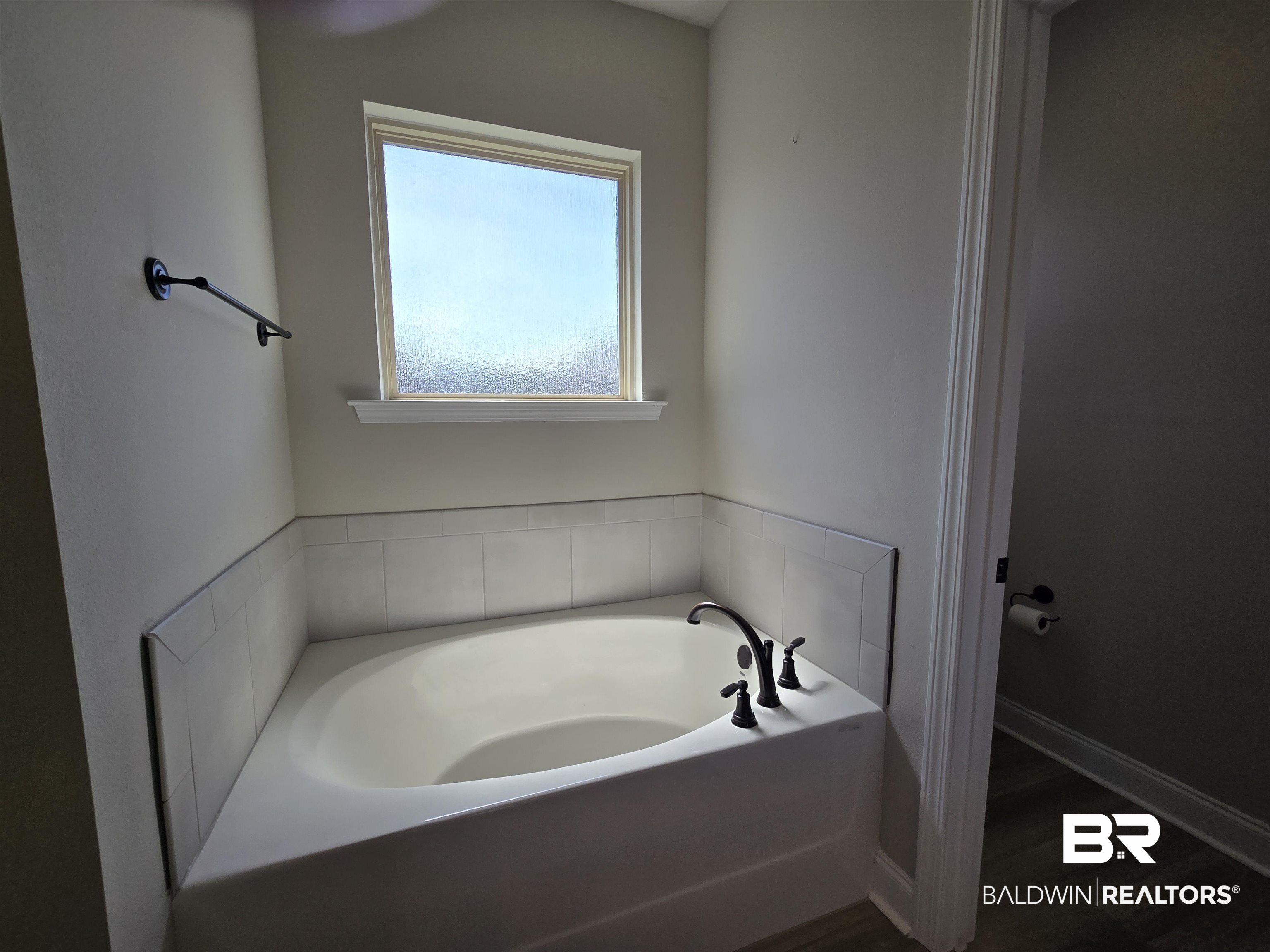 1060 Chloe Street Foley, AL 36535 - Photo 8 of 28 Corner soaking tub featuring a tiled surround, frosted window, and dark bronze fixtures