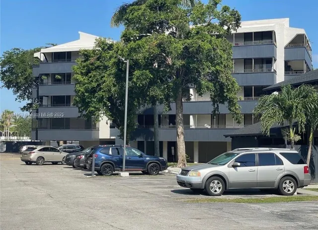 a front view of a building with cars parked